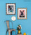 2 rabbit paintings framed in Opera champagne silver moulding displayed on a bright blue wall beside decorative silver chair.