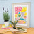 Modern art fish & chips print in a distressed white frame surrounded by potted plants