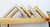 Gold and silver frame corner samples on a wooden shelf.