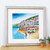 Bright beach and harbour art print in silver frame and white mount