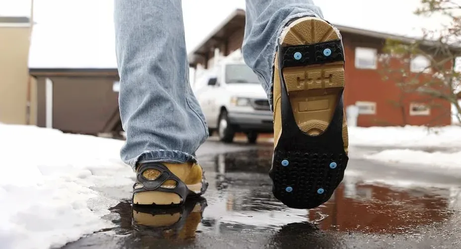 DueNorth strap-on studs on a work boot, stepping onto wet pavement