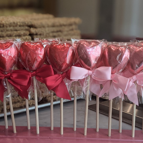 Foil wrapped heart shaped chocolates on wooden stick with bow in pink and red