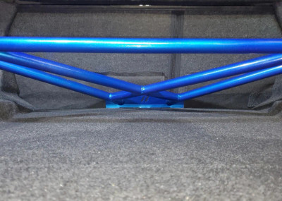 Downforce Solutions 4-point Apex rear trunk brace installed in a Dodge Challenger, showing lightweight aluminum construction and secure fit between rear shock towers.