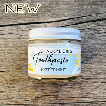 Photo of peppermint alkalizing toothpaste on wooden background  with graphic reading "new"