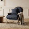 Montpellier occasional armchair by Thomas & Hurley in black linen and weathered oak, in a styled room with a black cushion and neutral linen throw.