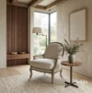 Curved Montpellier French-style armchair in linen upholstery and oak frame in a styled living room with garden view