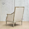 Rear angle showcasing the weathered oak frame and tufted detailing on the back of the natural linen armchair