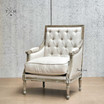 Diagonal view, capturing the chair's profile and tufted backrest in natural linen