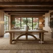 A hardwood timber dining table with curved base, the Trailbridge solid oak dining table by Thomas and Hurley, showed in a styled setting