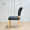 Side view of the Macallan Chair, showcasing the elegant curve of the gently flared back and the sleek timber legs.