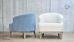 Rear and side view of the two chairs, one in blue chenille and the other in beige cream linen upholstery finish, placed back-to-back. This perspective emphasizes the differences in the upholstery and the weathered oak legs, offering a comprehensive comparison of the finishes.