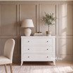 Styled front view image of the Piastri 3 Drawer Chest in white in a classic styled bedroom setting