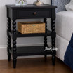 An angled detailed view of the Montclair Side Table in Black showcasing its bobbin leg detailing and functional drawer and display shelving.