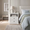 White wooden bedside table with cross molding details by Thomas and Hurley.