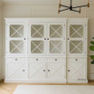 Somerset 4 Door Display Wall Unit in situ in living room, highlighting its Hamptons-inspired design, signature cross detailing on the doors, and spacious shelving, perfect for use as a display unit or bookshelf.