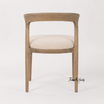 A premium timber dining chair with curved backrest and textured fabric seat by Thomas and Hurley for designer dining room styling.