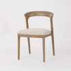 The Laguna Dining Chair by Thomas and Hurley with curved timber backrest and textured upholstered seat for contemporary luxury dining interiors.
