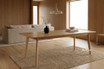 Solid oak timber large 240cm dining table in a styled contemporary interior showcasing tapered leg and oak timber grain