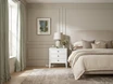 White Lando 3 Drawer bedside table styled with a sculptural table lamp and vase beside a bed, framed by sheer linen curtains and large windows in a light-filled bedroom.