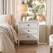 White Lando 3 Drawer bedside table styled with a ceramic lamp and decorative vase in a light-filled contemporary bedroom, offering generous bedside storage.