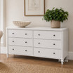 An angled styled view of the Brynmore 6 Drawer Chest in White, an elegant storage solution for either living room or bedroom spaces.