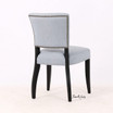 Upholstered dining chair with black legs and brass nailhead trim rear profile