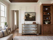 Curved blue chest of drawers with an aged painted finish beside dark timber cabinetry in an elegant living space