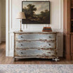 Blue bombe chest styled beneath framed artwork with decorative ceramics