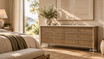 Contemporary classic chest of drawers with marble top and fluted drawers in a warm minimalist bedroom with natural light