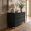 Contemporary classic black chest of drawers in a neutral panelled room