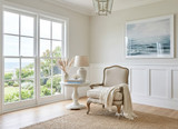 Sunny Hamptons living room with natural light, garden outlook, and coastal art by the Cannes linen occasional armchair by Thomas and Hurley