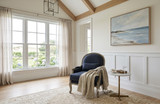 Curved black upholstered armchair with weathered oak frame in a styled living room with artwork and natural light