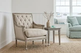 Luxury tufted armchair with cream upholstery and weathered oak legs by Thomas & Hurley in a calm Hamptons style living room