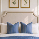 A close-up detailed view of a cream linen upholstered headboard in neutral linen tones, with studding detail.