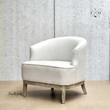 Angled front view  displaying the chair's timeless rounded silhouette in natural linen