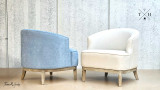 An angle shot capturing both chairs - the blue chenille and cream linen upholstery, highlighting the variations in texture and design details from a diagonal perspective.