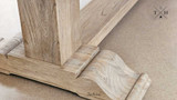 Image focusing on the robust pedestal legs of the Charlested Oak Dining Table, illustrating their solid build and elegant design.