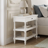 Luxury white wooden nightstand with bobbin legs styled with a ceramic lamp and books.