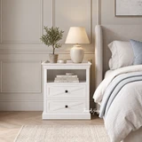 Hamptons style white bedroom nightstand set against pale paneled wainscoting.