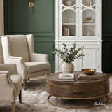 Darcy round oak coffee table by Thomas and Hurley centered between classic cream wingback chairs