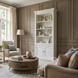 Tall white single bookcase wall unit with closed cabinet storage in a modern coastal living area