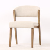 Three quarter front view of the Stanton Dining Chair in fabric, displaying its padded seat, clean lines and natural timber legs by Thomas & Hurley.