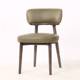 Three quarter front view of the Royston Dining Chair in Aston Green Leather featuring top grain green leather upholstery and minimalist blackwash timber frame.