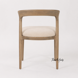 A premium timber dining chair with curved backrest and textured fabric seat by Thomas and Hurley for designer dining room styling.