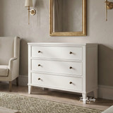 White Lando 3 Drawer Chest styled beneath a gold framed mirror in a contemporary living room, showcasing spacious storage, classic panel detailing and bronze knobs.