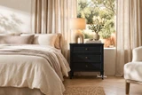 Premium black bedside chest with traditional panelled drawer fronts in a contemporary bedroom with natural light