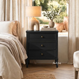 Three drawer black bedside cabinet with refined architectural lines in a styled bedroom setting
