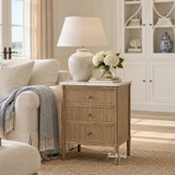 Marble top side table with three drawers and classic detailing styled with a lamp and flowers in a Hamptons living room