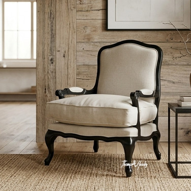 Cannes Occasional Armchair featuring carved black armrests and neutral linen seating in a warm styled living room with art and wood panelling