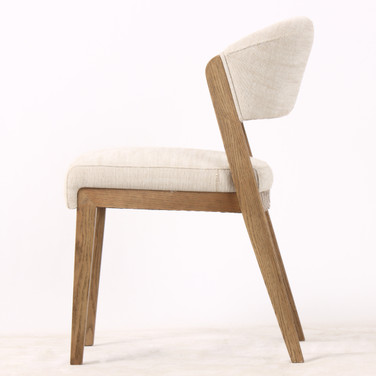 Side profile of the Stanton Dining Chair featuring a gently curved backrest and solid natural wood legs, ideal for modern dining tables.